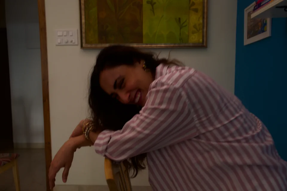 Sabah smiling as she rests her arms on a chair
