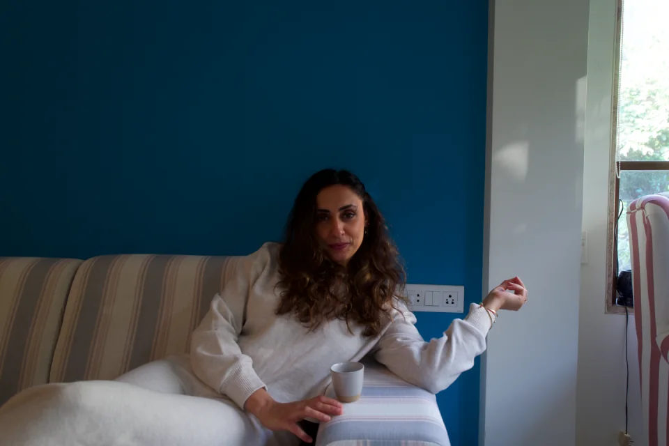 Sabah seated with a cup, gesturing in conversation