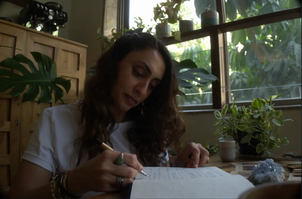 Sabah writing at a table beside plants